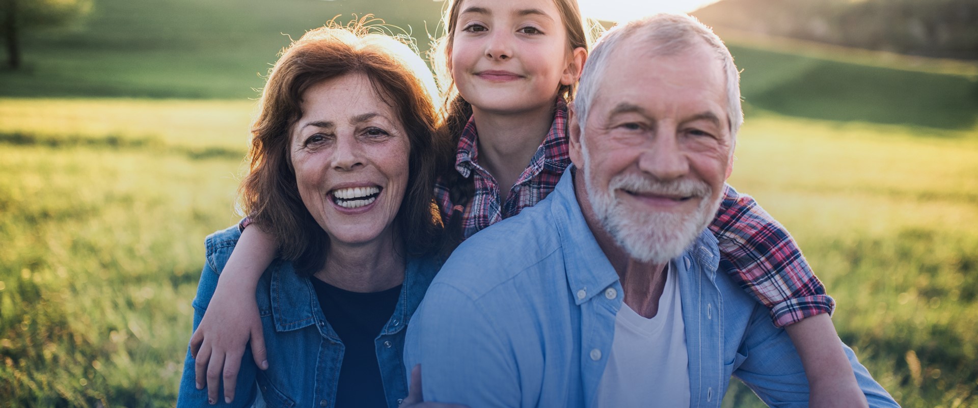 Elderly woman and man smiling with their grandaughter outside